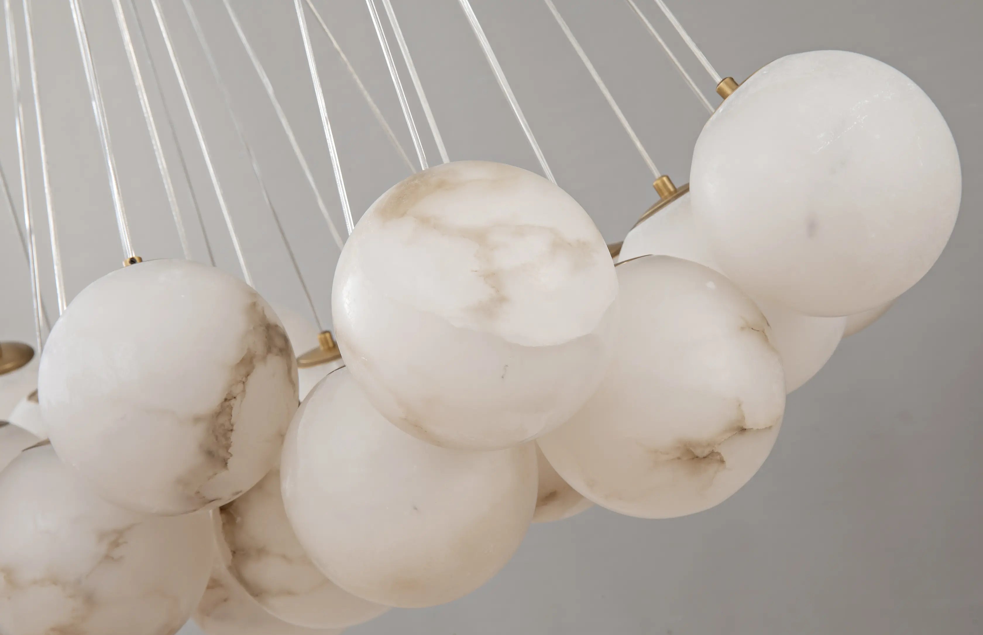 Close-up of a marble pendant light fixture with spherical marble balls on a neutral background.